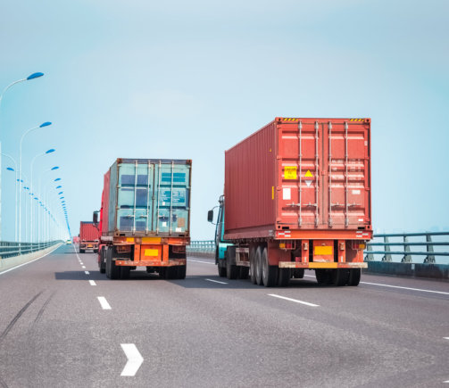 3 visible cargo trucks running in a highway road